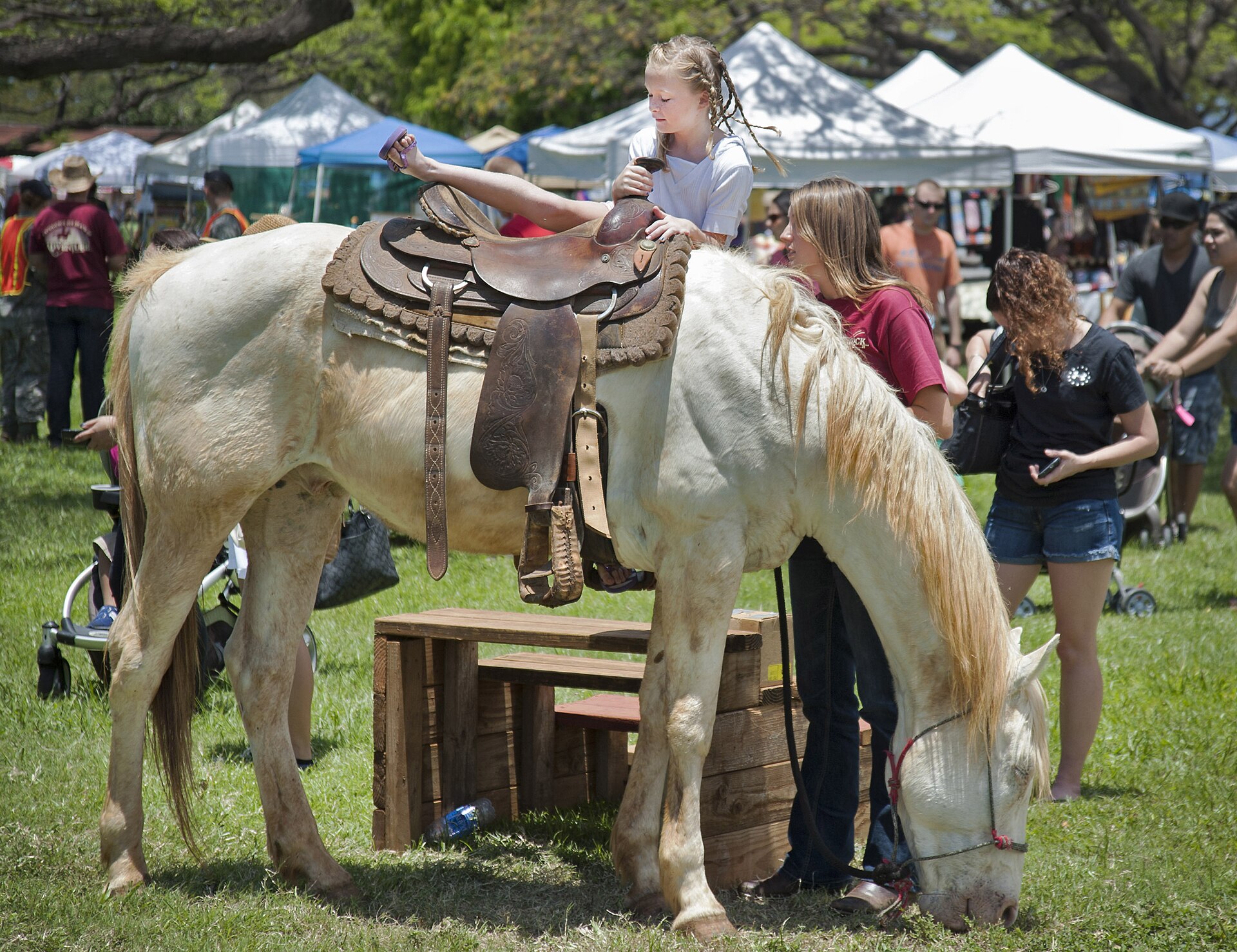 Visitors walking past booths at a community craft fair.